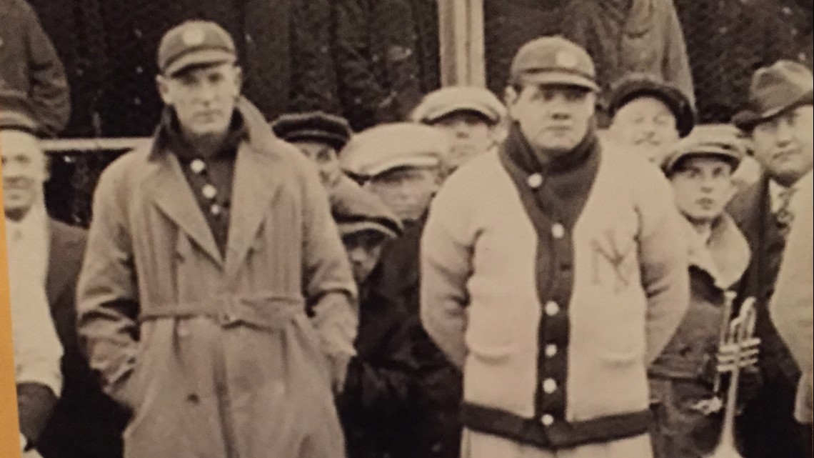 Babe Ruth holding a baseball bat as a boy in a baseball uniform looks on —  Calisphere