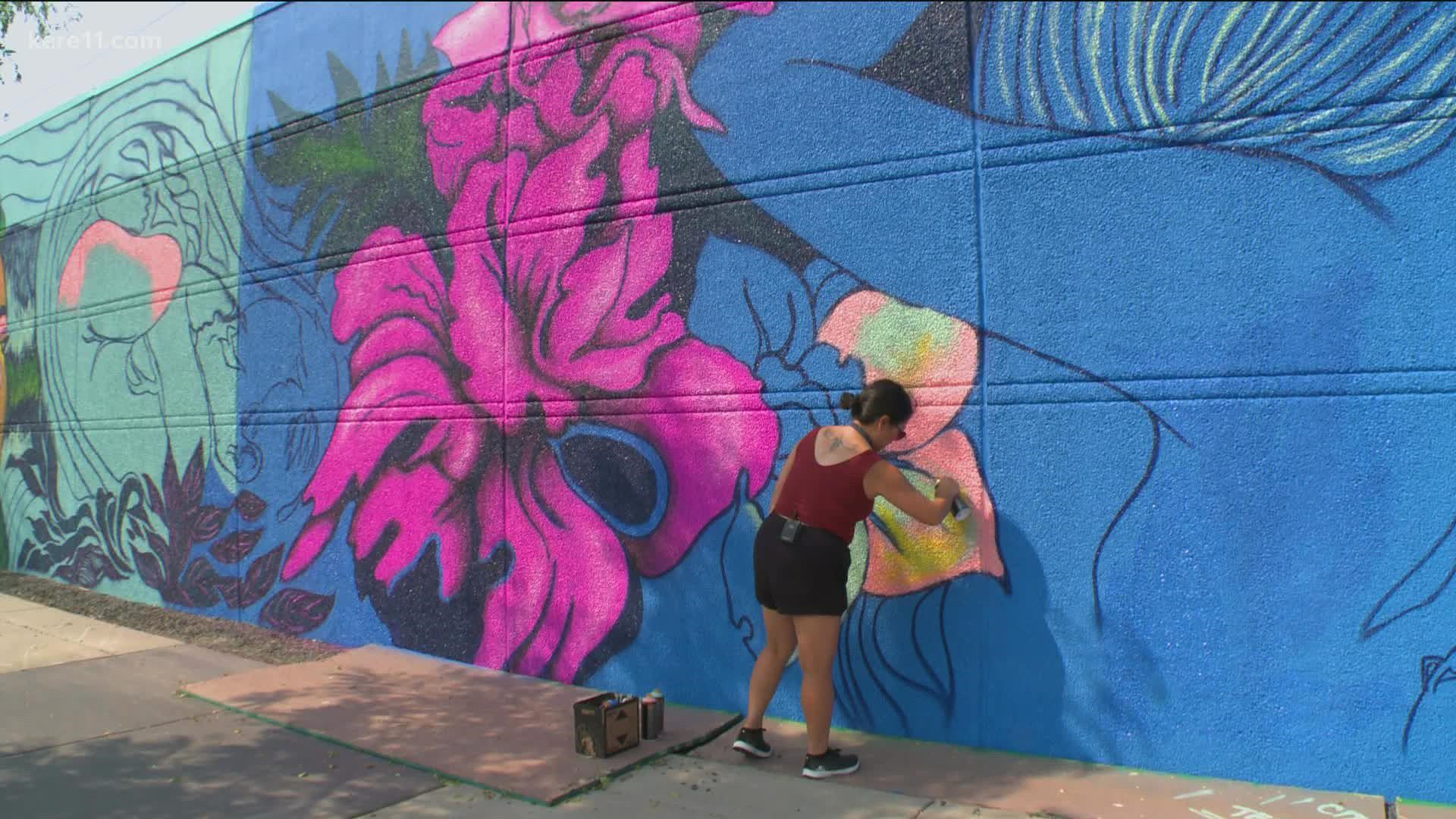 Local visual artists are currently working on the WE mural, located in the South Loop neighborhood of Bloomington