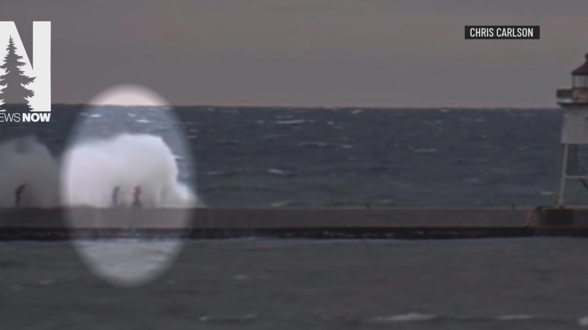 Chris Carlson was fishing on Grand Marais Harbor Sunday when he saw three people walking on a pier. A huge wave crashed, sweeping one of them into Lake Superior.