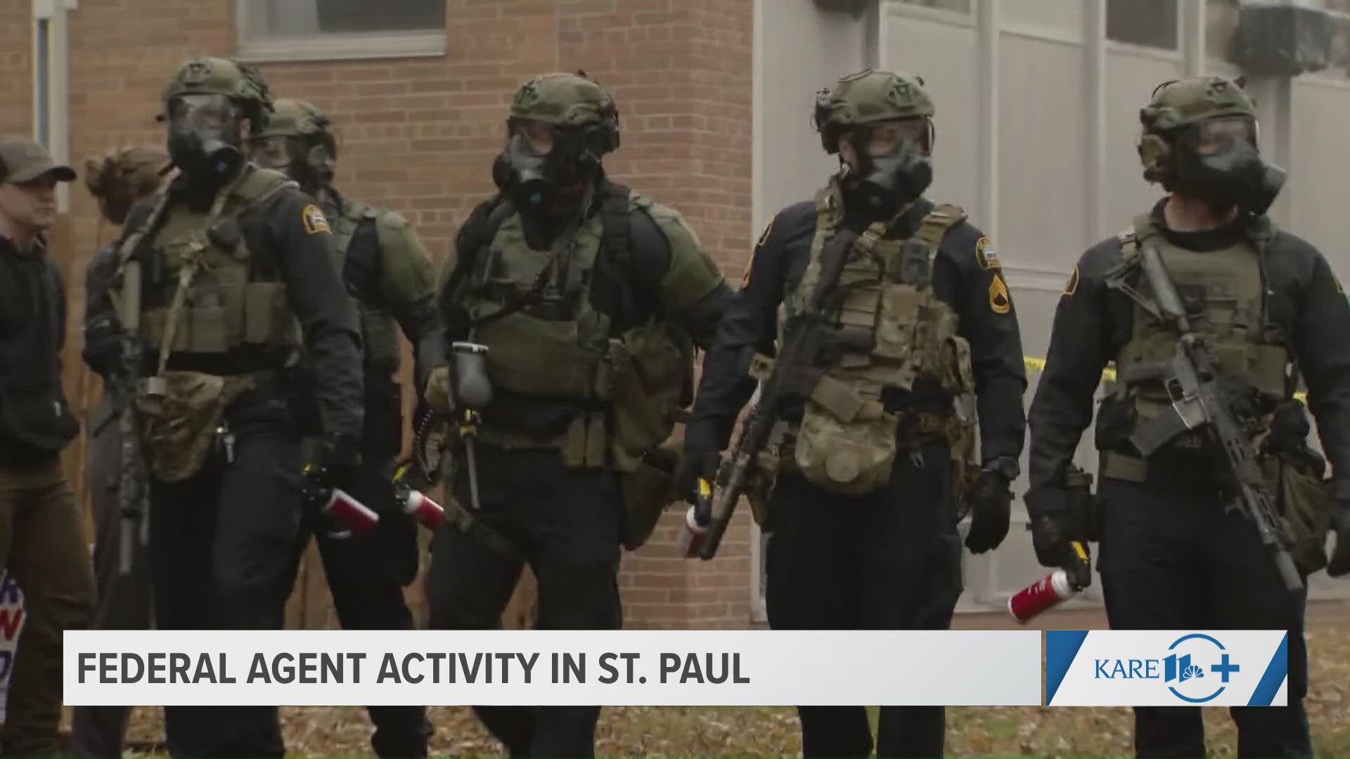 Officers formed a line outside a St. Paul home raided by federal agents, monitoring a peaceful crowd with no confrontations in this moment.